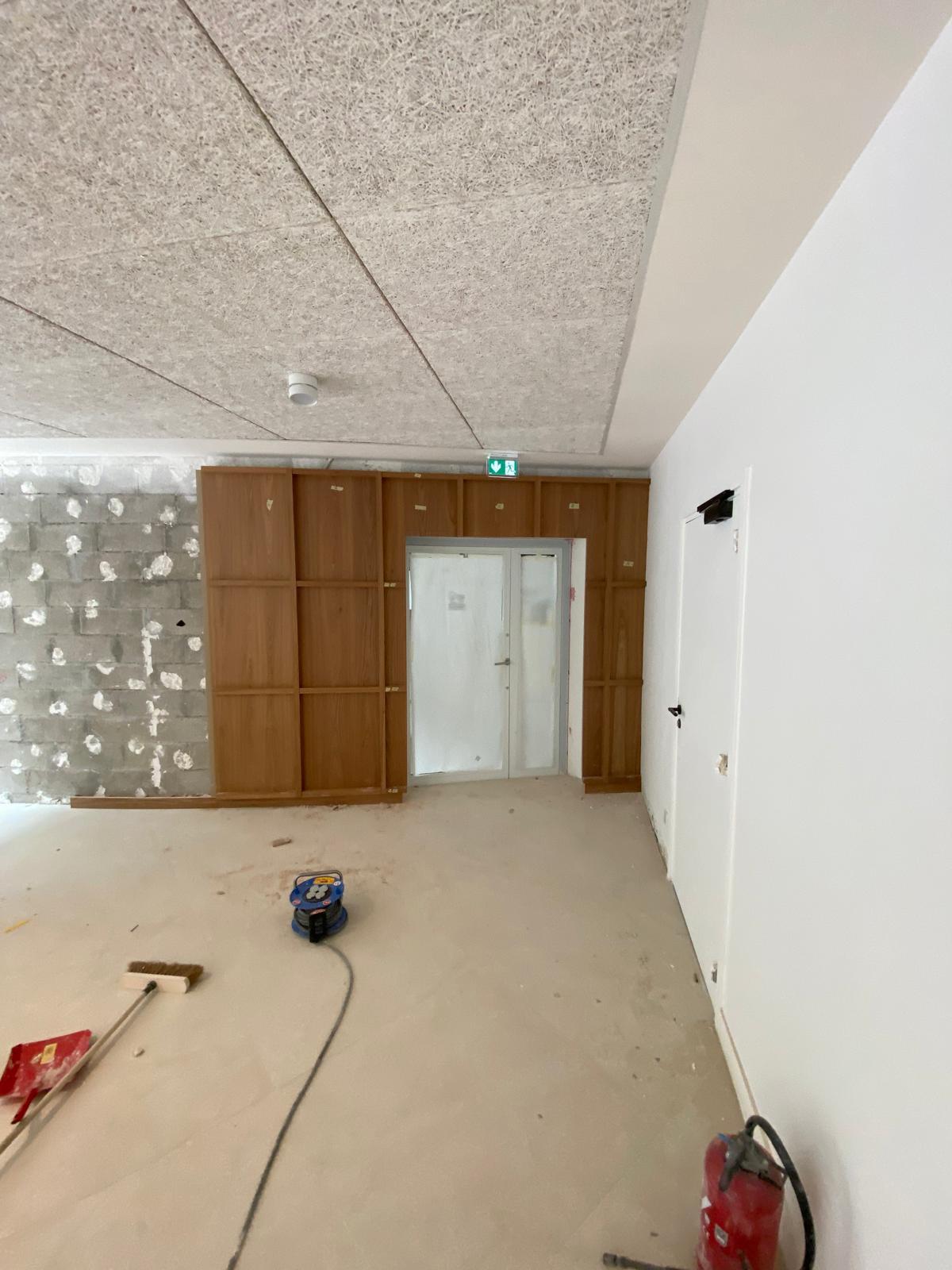 Pose de l'habillage bois sur le mur brut, en cours de chantier.