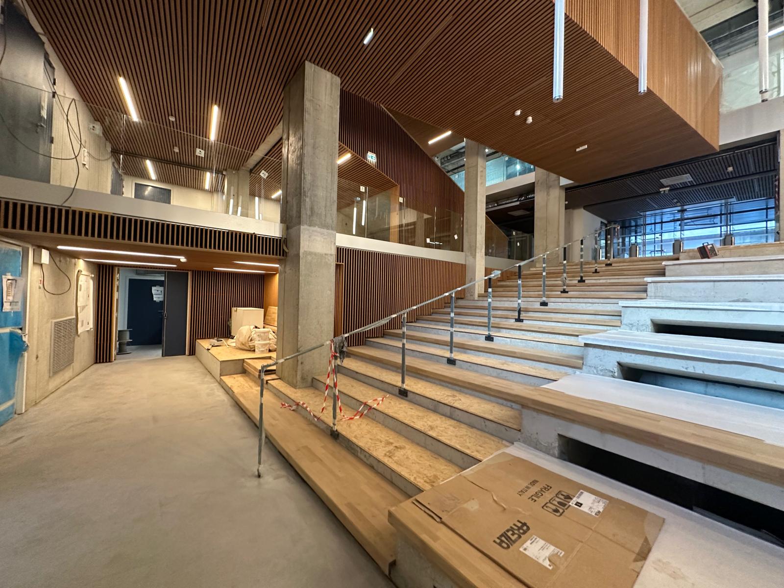 Hall et gradins sous le plafond bois, vue d'ensemble.