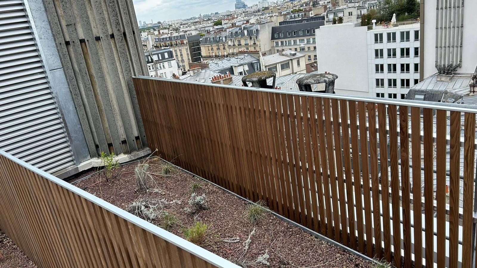 Le platelage bois bordé de jardinières et de garde-corps verre.